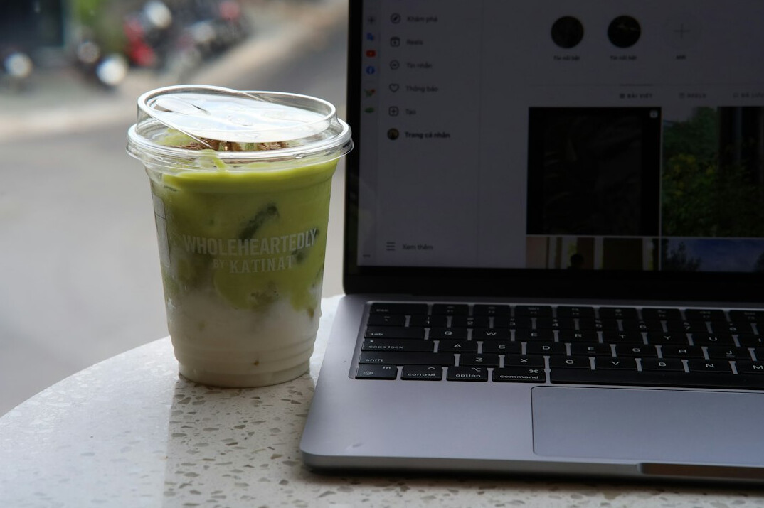 Laptop with code on screen next to a notebook and coffee